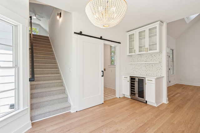 380 Tidal Reef Cir, Mount Pleasant, SC 29464 - bar with beverage cooler, a barn door, light wood-style flooring, stairs, and a chandelier