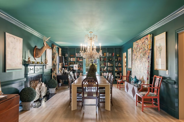 dining area featuring crown molding, wood finished floors, a notable chandelier, and a fireplace