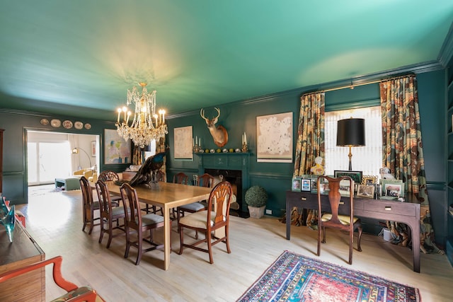 dining area with an inviting chandelier, crown molding, and wood finished floors