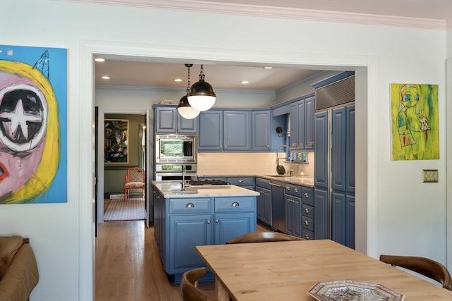 kitchen featuring crown molding, a sink, built in appliances, an island with sink, and blue cabinets