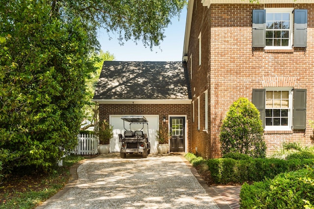 view of front of home with brick siding, fence, and driveway