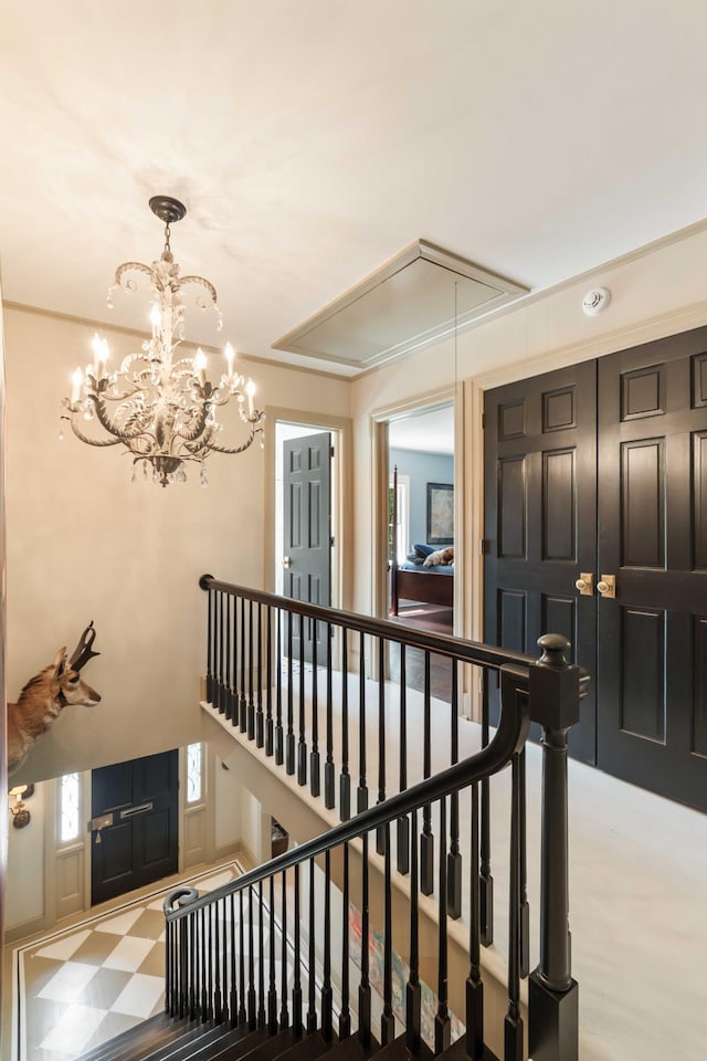 staircase featuring attic access and a chandelier