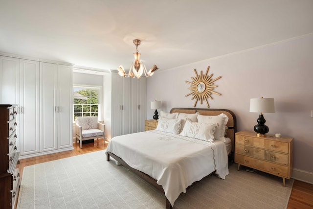 bedroom featuring crown molding, baseboards, a chandelier, and light wood-type flooring