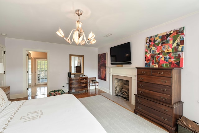 bedroom with baseboards, a fireplace, wood finished floors, and a chandelier