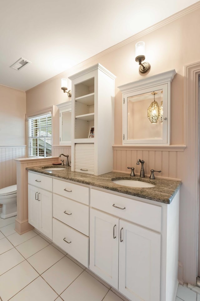 bathroom with visible vents, a sink, a wainscoted wall, and double vanity