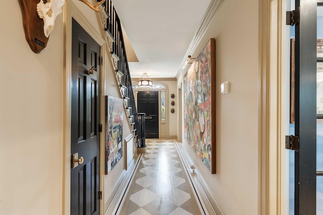 corridor with crown molding, baseboards, and light floors