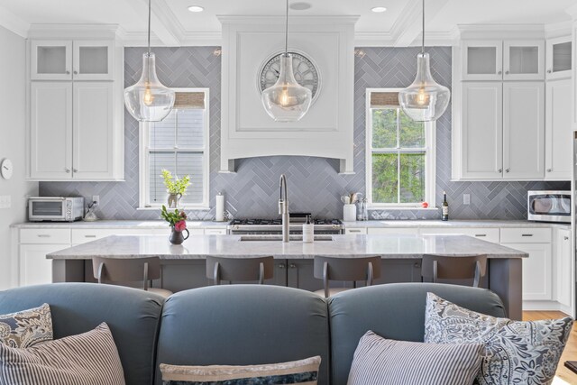 112 Berkshire Dr, Wando, SC 29492 - kitchen featuring crown molding, stainless steel microwave, a center island with sink, and tasteful backsplash