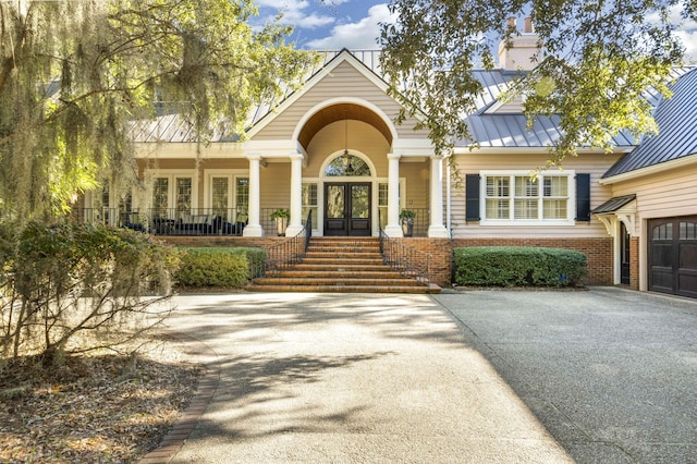 doorway to property featuring aphalt driveway, french doors, metal roof, and a standing seam roof