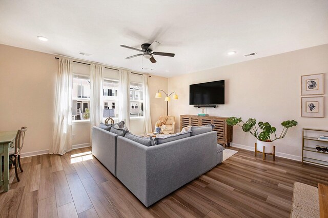 living area featuring baseboards, visible vents, wood finished floors, and ceiling fan