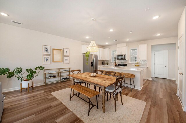 dining room featuring baseboards, light wood-type flooring, visible vents, and recessed lighting
