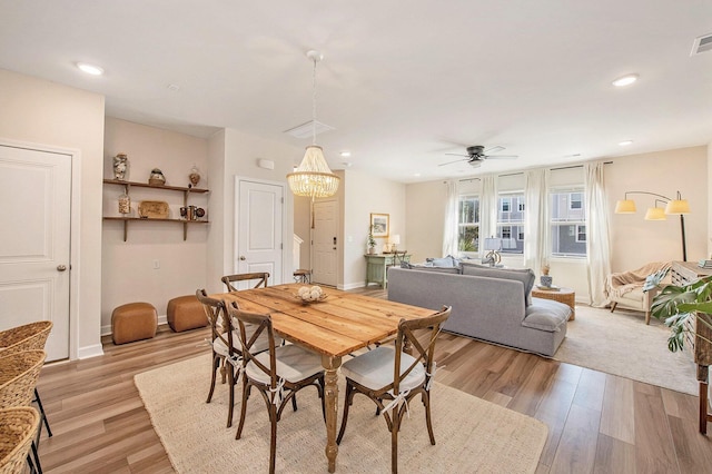 dining area with light wood-style flooring, ceiling fan with notable chandelier, baseboards, and recessed lighting
