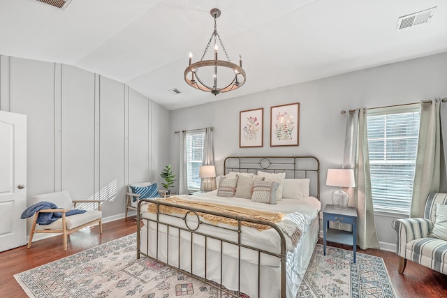 bedroom with hardwood / wood-style flooring, an inviting chandelier, multiple windows, and vaulted ceiling