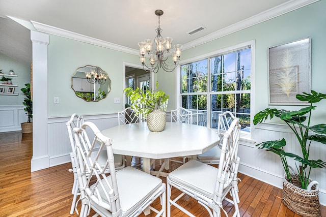 dining space with visible vents, wainscoting, ornamental molding, wood finished floors, and a chandelier