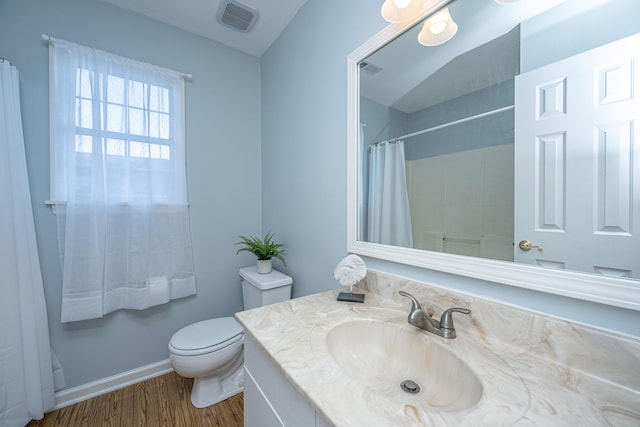 bathroom featuring curtained shower, visible vents, toilet, vanity, and wood finished floors