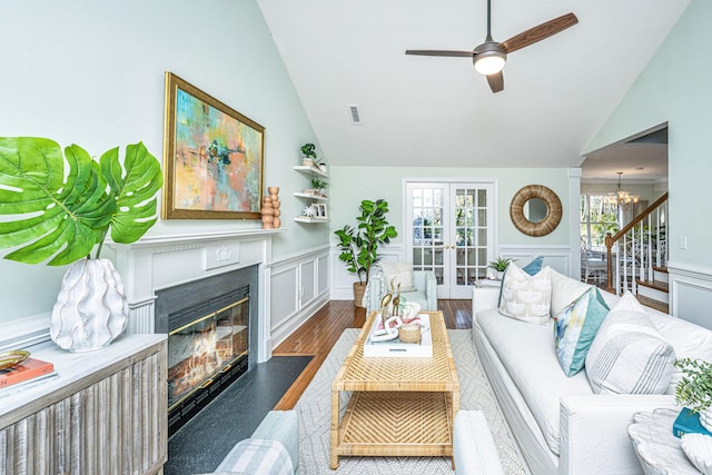 living room featuring french doors, a wainscoted wall, dark wood finished floors, stairway, and a glass covered fireplace