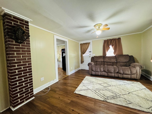 living room with brick wall, dark hardwood / wood-style flooring, ceiling fan, and crown molding