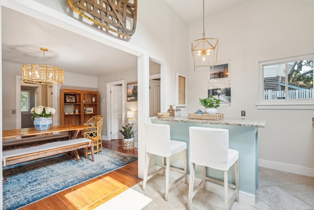 dining area with light hardwood / wood-style flooring, a towering ceiling, and a chandelier