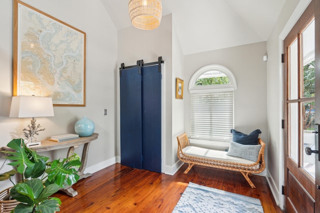 sitting room featuring lofted ceiling, dark wood-type flooring, and a barn door