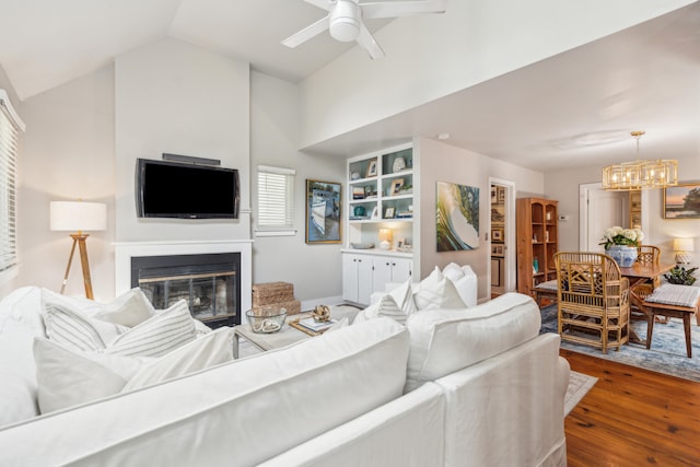 living room featuring ceiling fan with notable chandelier, dark hardwood / wood-style floors, and vaulted ceiling