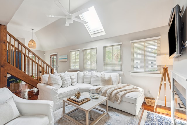 living room featuring light hardwood / wood-style floors, ceiling fan, and lofted ceiling with skylight