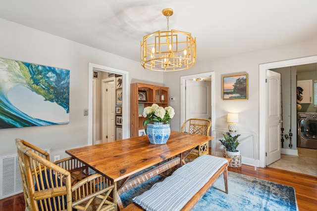 dining area featuring a notable chandelier, washer / dryer, and hardwood / wood-style flooring