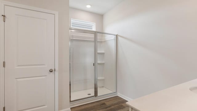 bathroom with hardwood / wood-style flooring and a shower with shower door