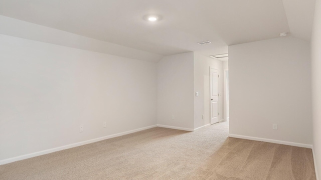 spare room featuring light colored carpet and vaulted ceiling