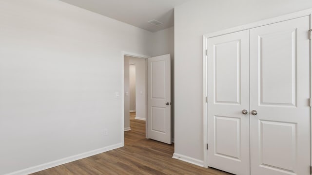 unfurnished bedroom with dark hardwood / wood-style flooring and a closet