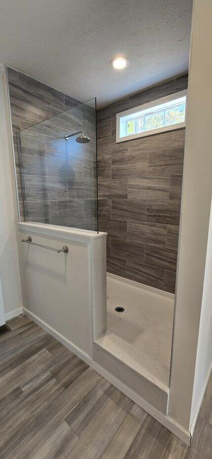 bathroom featuring wood-type flooring, a textured ceiling, and tiled shower