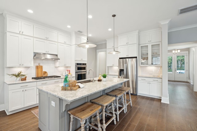 kitchen featuring white cabinetry, a kitchen island with sink, hanging light fixtures, and appliances with stainless steel finishes