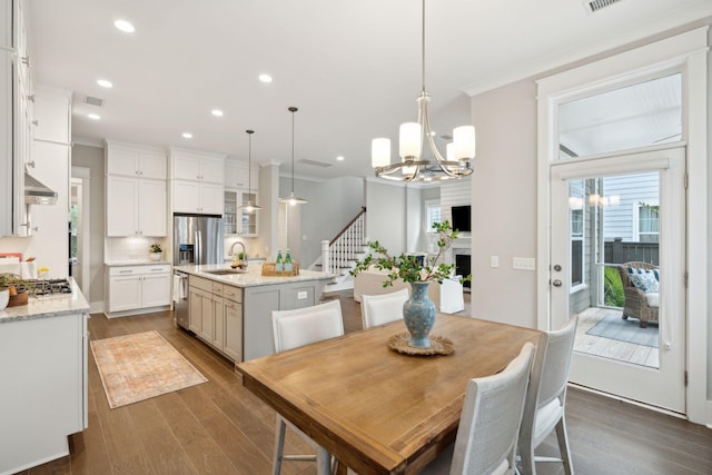 dining area with a healthy amount of sunlight, crown molding, sink, and dark wood-type flooring