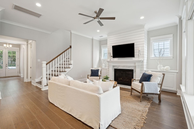 living room with plenty of natural light, ornamental molding, and a high end fireplace