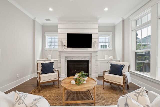 living room featuring a wealth of natural light, crown molding, a high end fireplace, and dark hardwood / wood-style floors