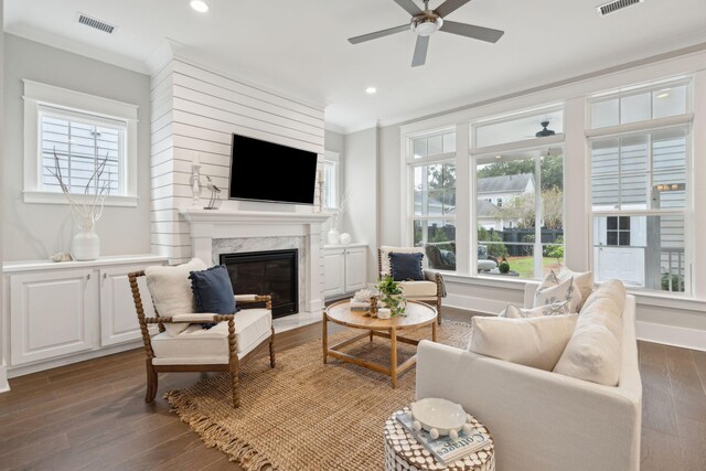 living room featuring crown molding, a fireplace, ceiling fan, and dark hardwood / wood-style floors