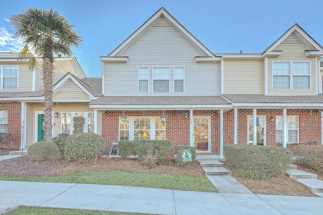 multi unit property featuring roof with shingles and brick siding