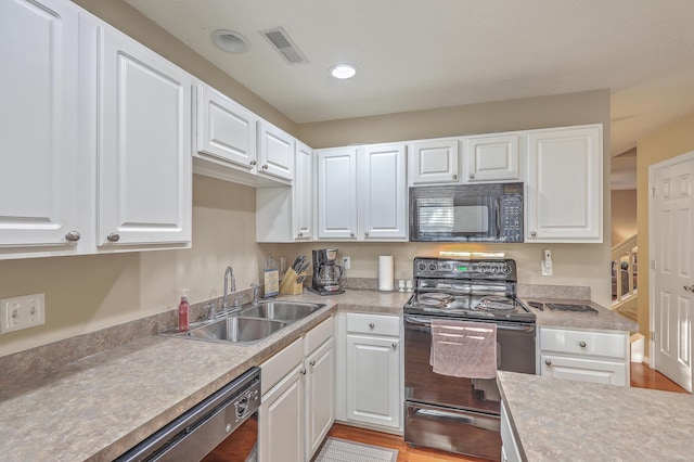 kitchen with black appliances, a sink, visible vents, and white cabinets