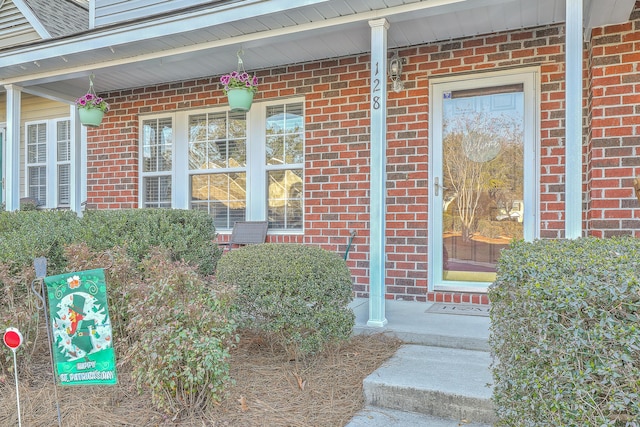 property entrance featuring covered porch and a shingled roof