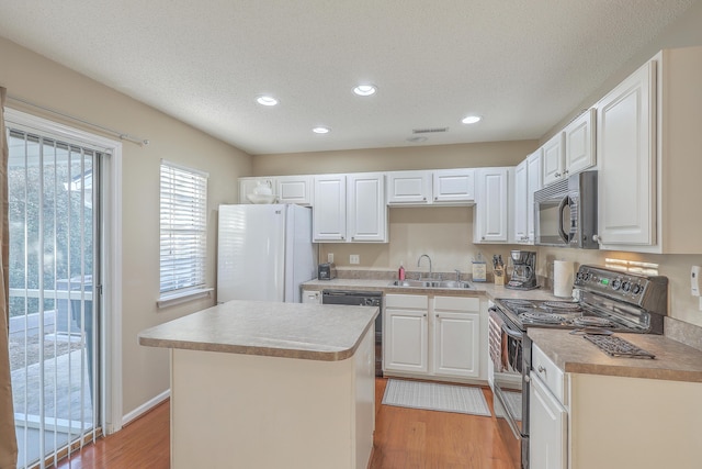 kitchen with dishwasher, stainless steel electric range oven, freestanding refrigerator, black microwave, and a sink