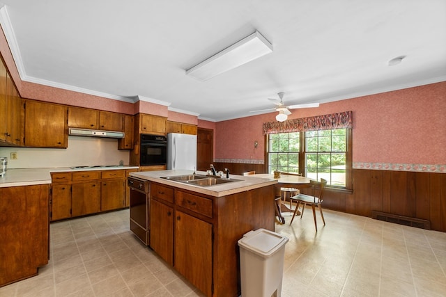 kitchen featuring white refrigerator, ceiling fan, a center island with sink, sink, and ornamental molding