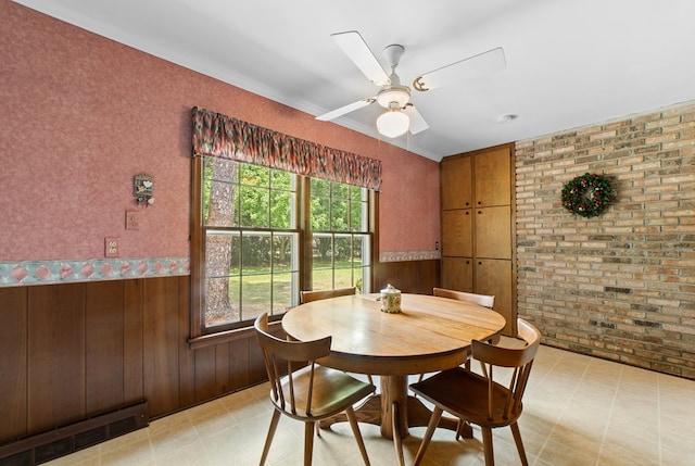 dining area featuring brick wall, wooden walls, and ceiling fan