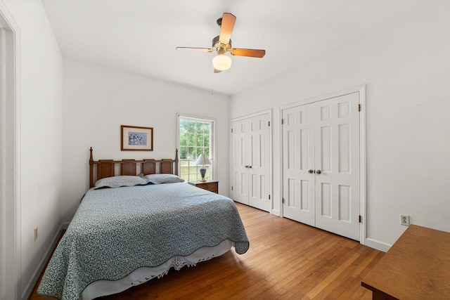 bedroom featuring light wood-type flooring, ceiling fan, and multiple closets