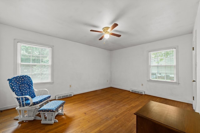 living area with ceiling fan, hardwood / wood-style flooring, and plenty of natural light