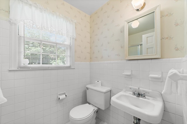 bathroom with sink, toilet, and tile walls