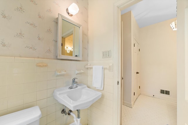 bathroom featuring sink, tile walls, and toilet