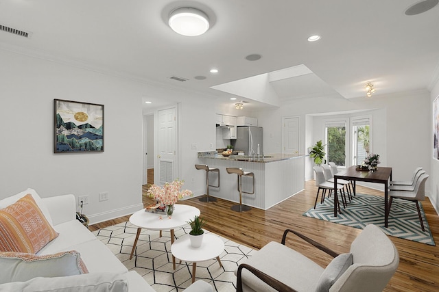 kitchen with under cabinet range hood, stainless steel appliances, visible vents, a sink, and a peninsula