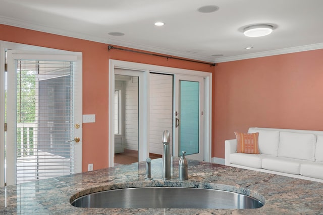 kitchen with ornamental molding, stone countertops, and sink