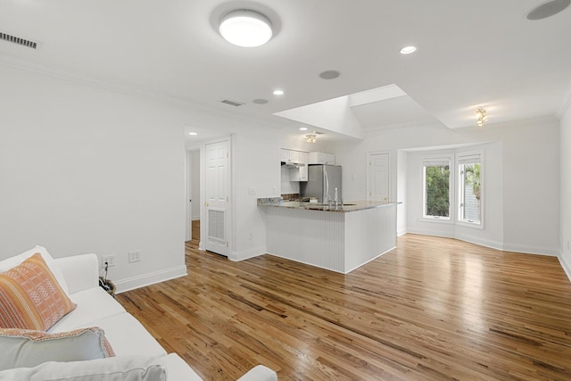 living room featuring light wood finished floors, baseboards, and ornamental molding