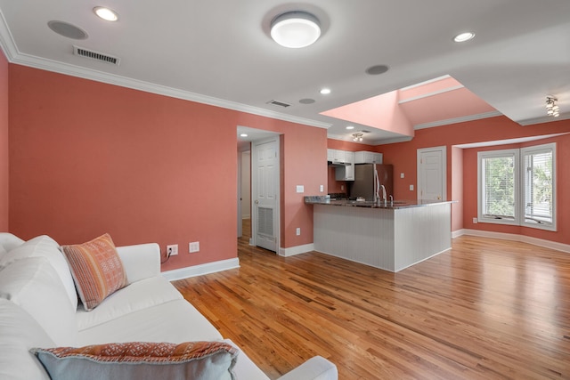 living room with crown molding, sink, and light wood-type flooring