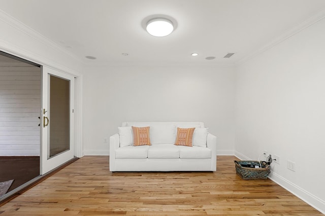living room featuring baseboards, light wood-style flooring, visible vents, and ornamental molding