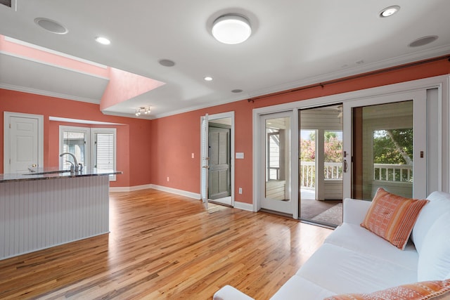 living room featuring crown molding, sink, and light hardwood / wood-style flooring